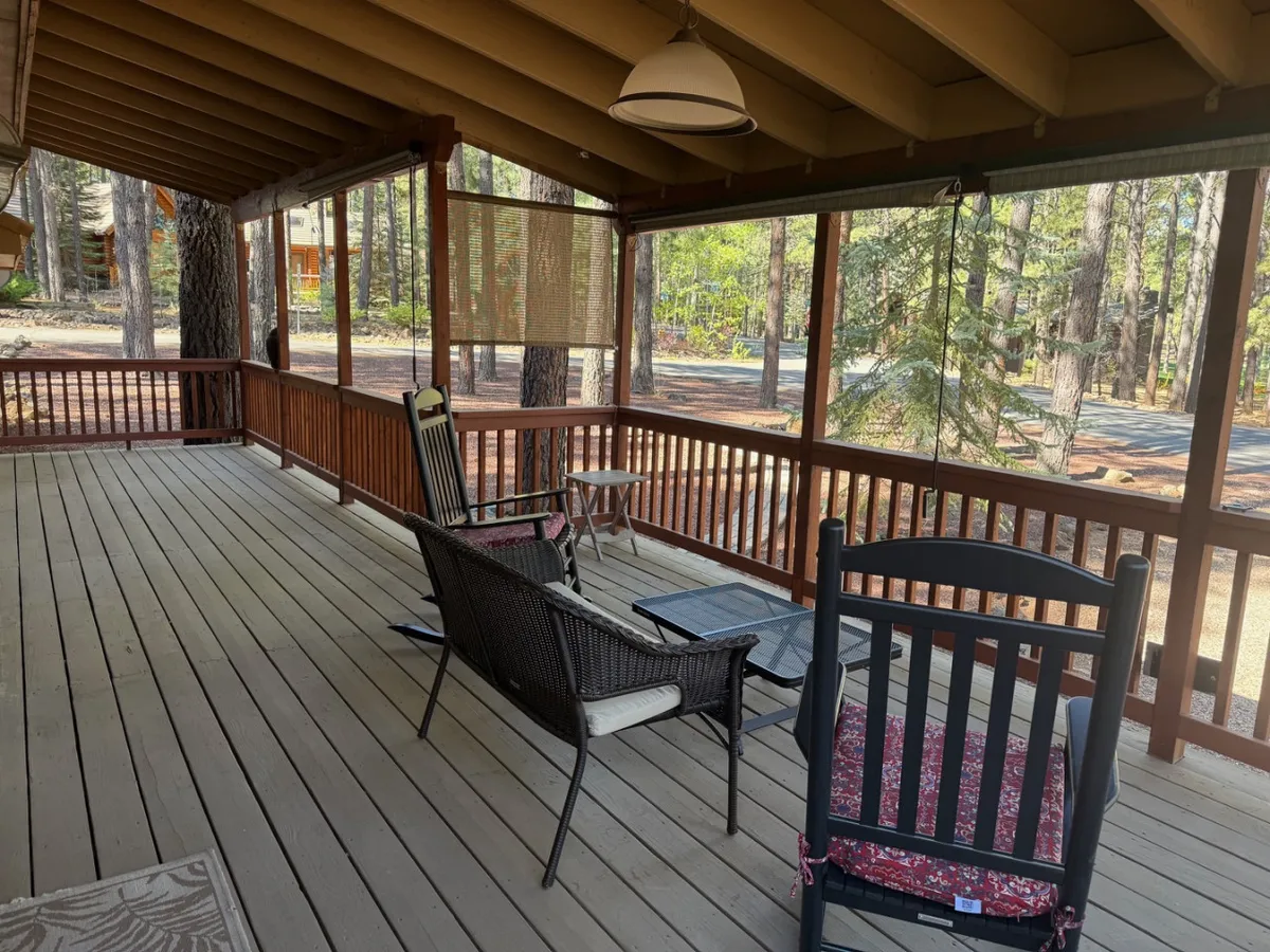 Set in a tranquil corner of the wrap-around porch, this image showcases a pair of rocking chairs and a coffee table within a screened enclosure. The design offers an intimate vantage point for quiet relaxation, reading, or enjoying a morning beverage while staying connected to the outdoors.
