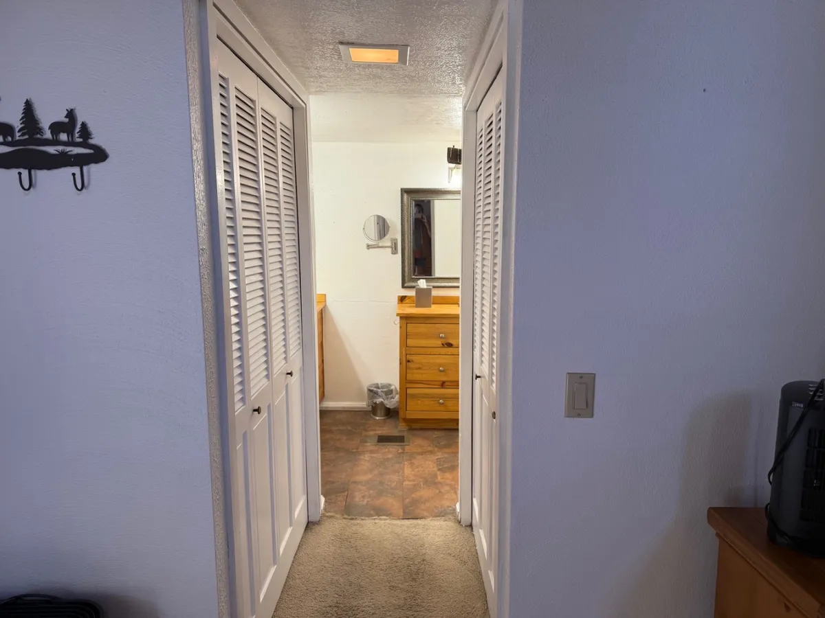 A cozy hallway scene with a dresser, mirror, and closet doors. The space feels intimate and functional, suggesting moments spent preparing for the day or unwinding after activities. Soft lighting and homey touches add to the welcoming vibe.