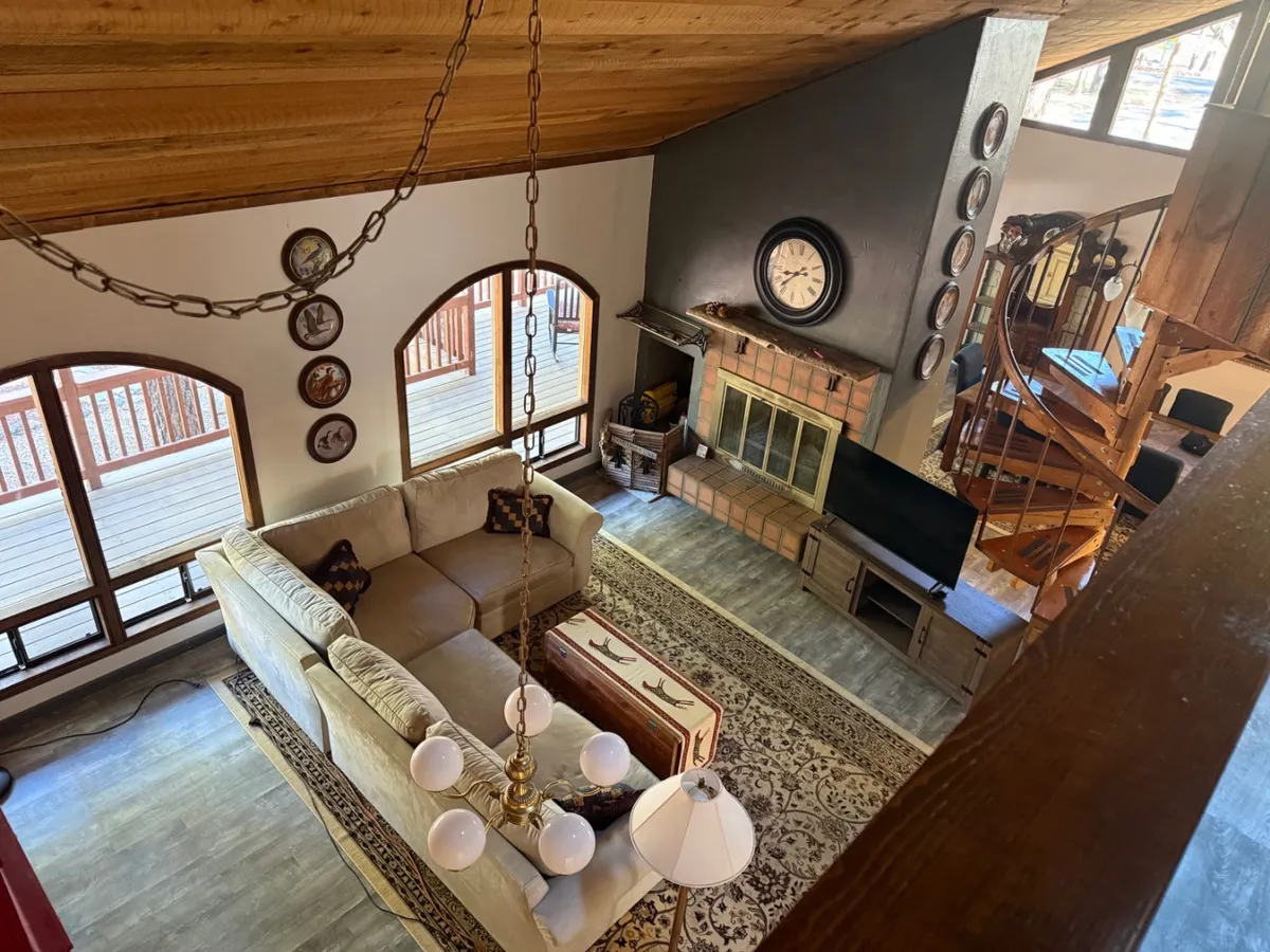 A welcoming living room with a comfortable sofa, a glowing fireplace, and a staircase leading upstairs. Decorative wall plates add a personal touch, while the room’s layout encourages relaxation, conversation, and cozy evenings by the fire.